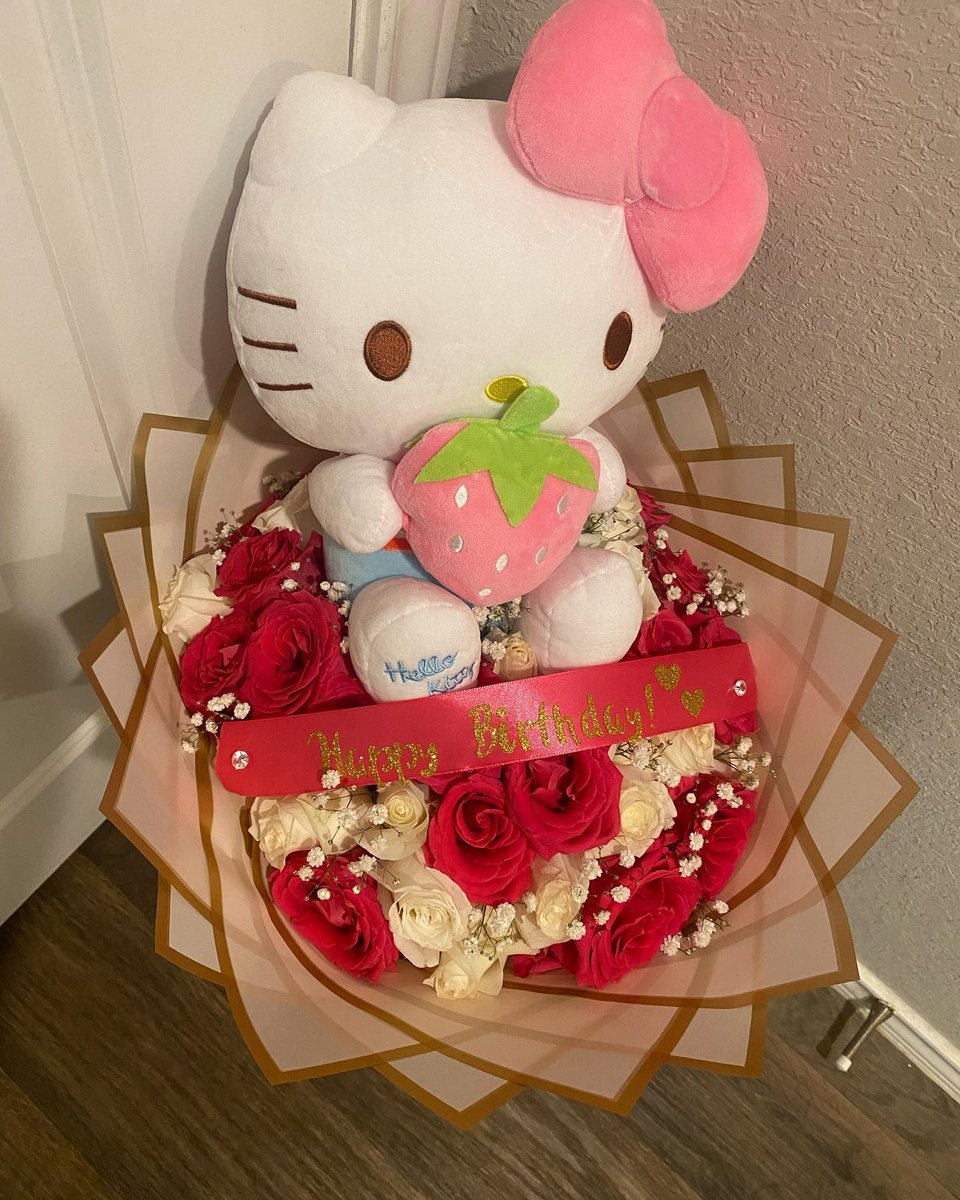Hello Kitty strawberry plush seated in red and cream roses